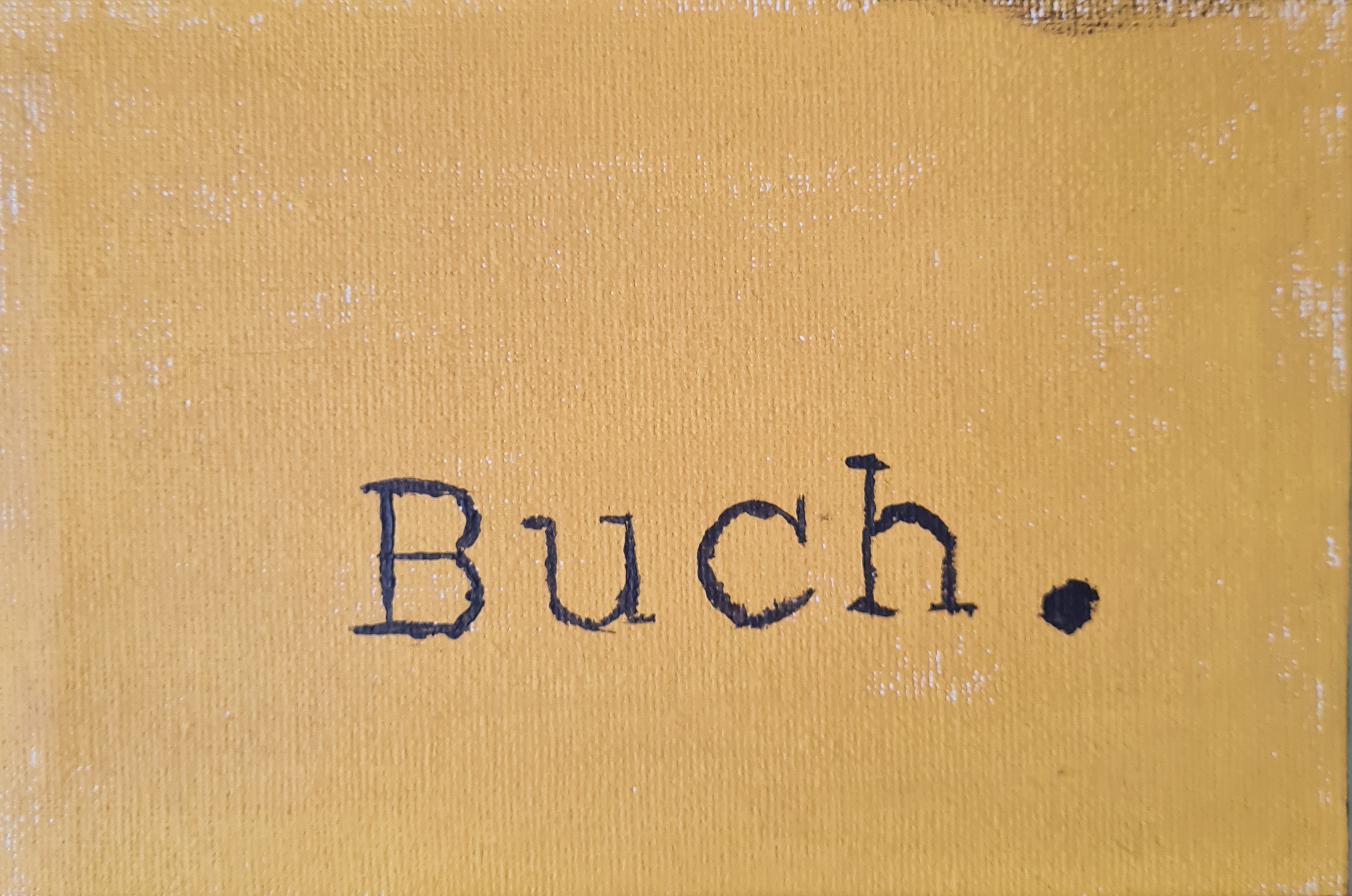 Leinwand, gelb bemalt, darauf gedruckter Text: Buch.