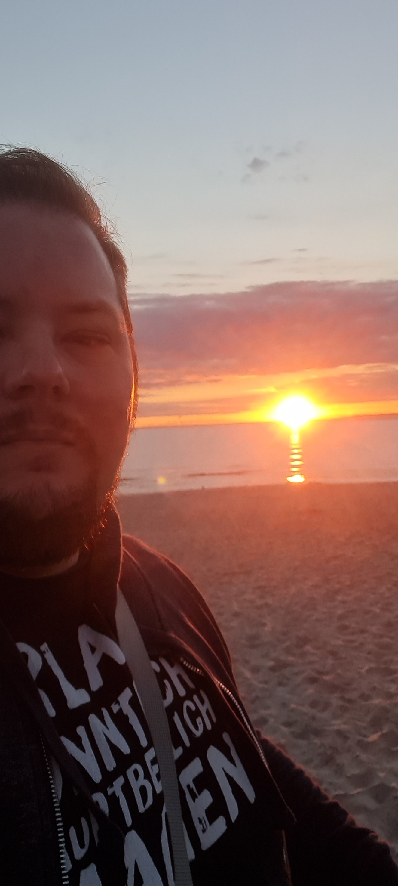 Ingo S. Anders vor einem Sonnenaufgang am Strand.